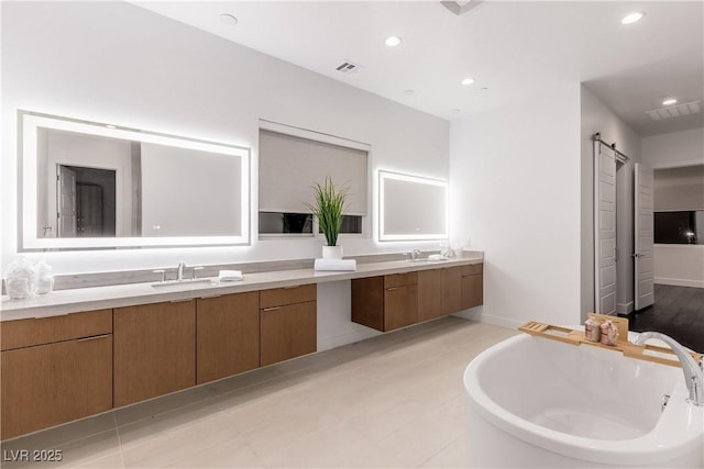 bathroom featuring visible vents, a freestanding tub, two vanities, and a sink