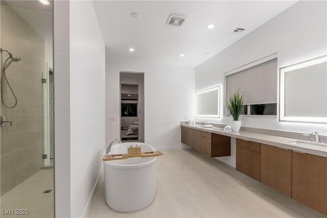 full bathroom with visible vents, tiled shower, double vanity, and a sink