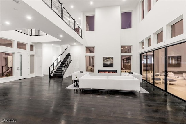interior space with a high ceiling, stairs, wood finished floors, and french doors