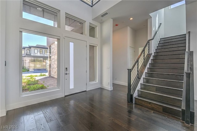 entryway with wood finished floors, stairway, baseboards, visible vents, and a high ceiling