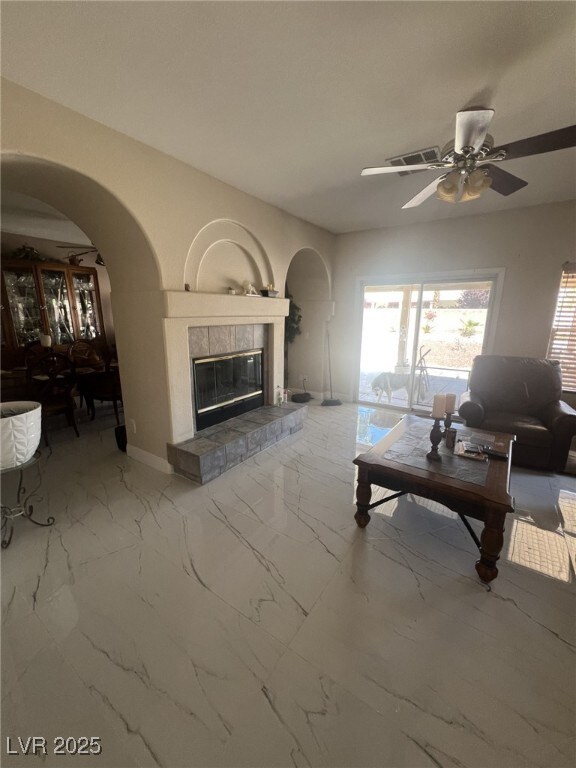 6596 Secluded Ave, Las Vegas, NV 89110 - living area featuring arched walkways, marble look tiles, ceiling fan, and a tiled fireplace