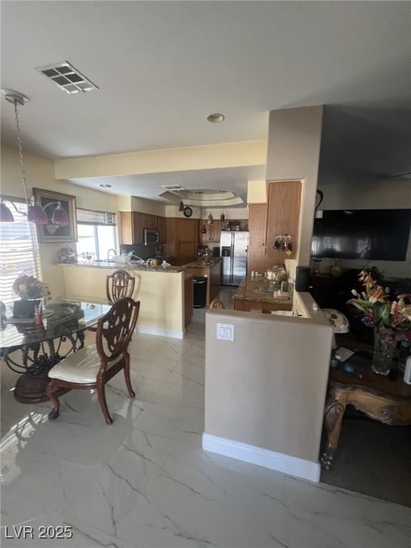 6596 Secluded Ave, Las Vegas, NV 89110 - kitchen with a peninsula, light marble finish floors, stainless steel appliances, and brown cabinets
