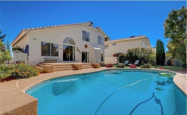 rear view of house with stucco siding, an outdoor pool, and a patio area