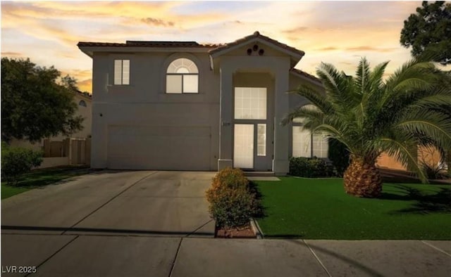 view of front of house featuring a front lawn, stucco siding, concrete driveway, and an attached garage