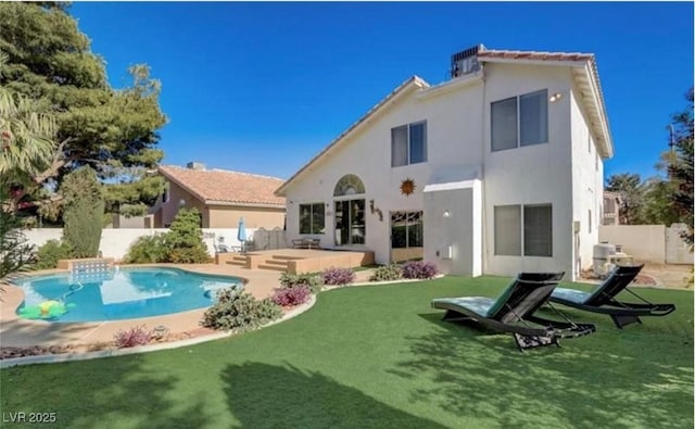 rear view of property with stucco siding, a lawn, and a fenced backyard