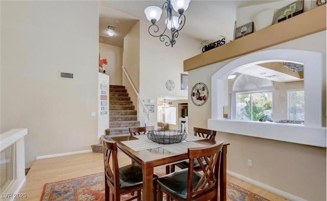 dining space featuring wood finished floors, arched walkways, stairs, visible vents, and a notable chandelier