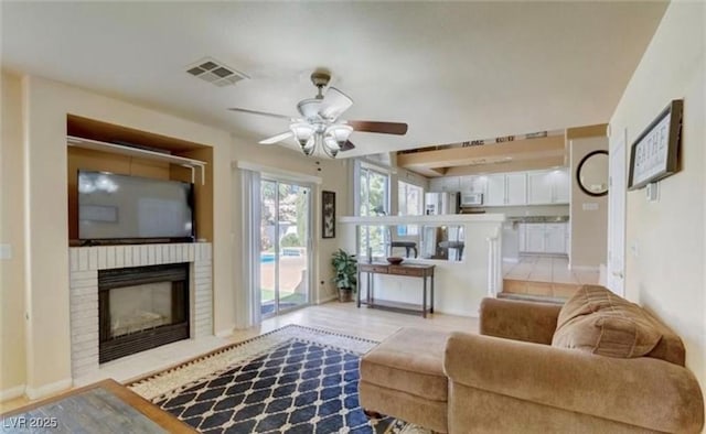 living room with visible vents, ceiling fan, baseboards, and a brick fireplace
