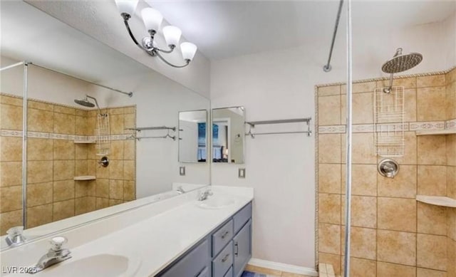 bathroom featuring tiled shower, double vanity, and a sink