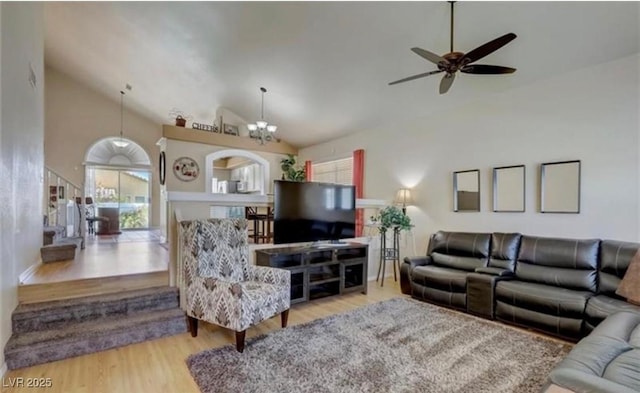 living area featuring a healthy amount of sunlight, wood finished floors, lofted ceiling, and ceiling fan with notable chandelier