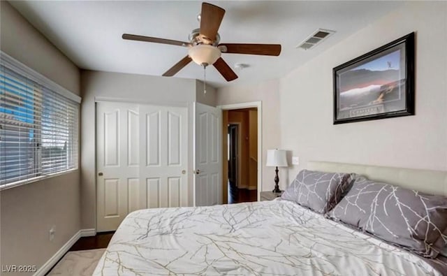 bedroom with baseboards, visible vents, a ceiling fan, and a closet