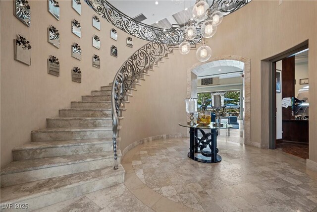 9301 Verlaine Ct, Las Vegas, NV 89145 - staircase featuring a chandelier, a towering ceiling, baseboards, and stone tile flooring