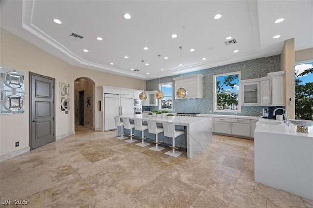 9301 Verlaine Ct, Las Vegas, NV 89145 - kitchen featuring a breakfast bar area, a center island, visible vents, built in appliances, and arched walkways
