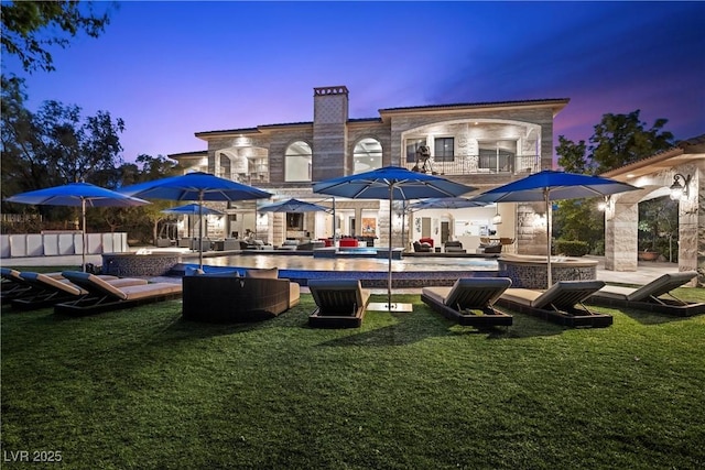 9301 Verlaine Ct, Las Vegas, NV 89145 - back of property at dusk featuring a yard, an outdoor pool, an outdoor living space, and a balcony