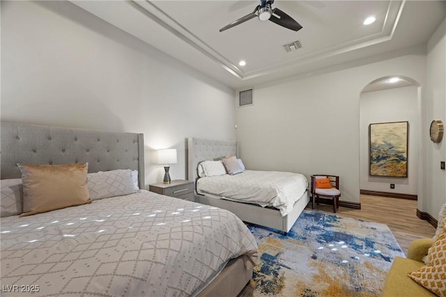 9301 Verlaine Ct, Las Vegas, NV 89145 - bedroom with wood finished floors, visible vents, recessed lighting, arched walkways, and a tray ceiling
