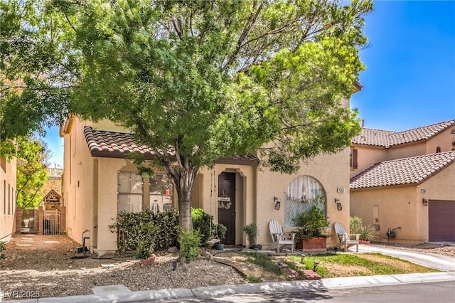 view of front of house featuring fence, stucco siding, a tile roof, and an attached garage