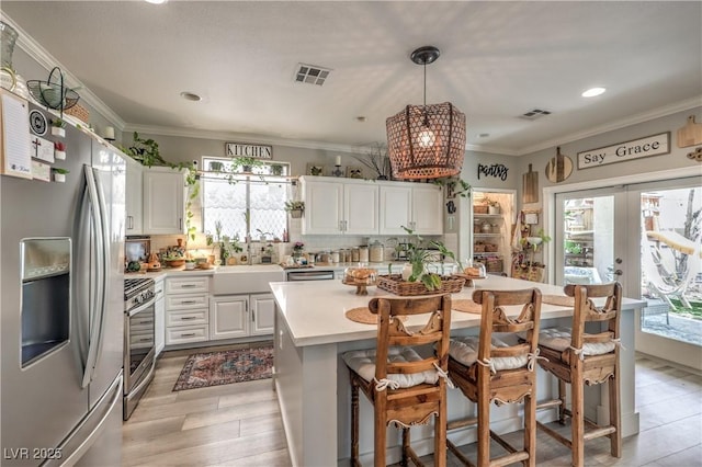 kitchen featuring decorative backsplash, appliances with stainless steel finishes, light countertops, a sink, and white cabinetry