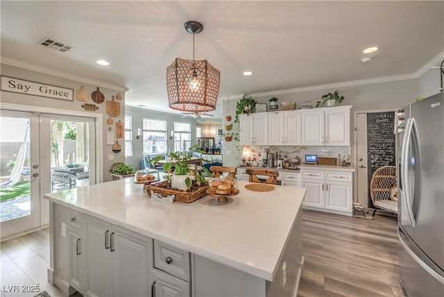 kitchen with ornamental molding, visible vents, white cabinets, and freestanding refrigerator