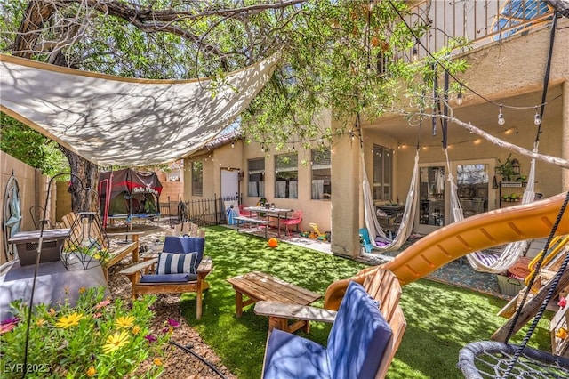 exterior space with a trampoline, a fenced backyard, and a patio area