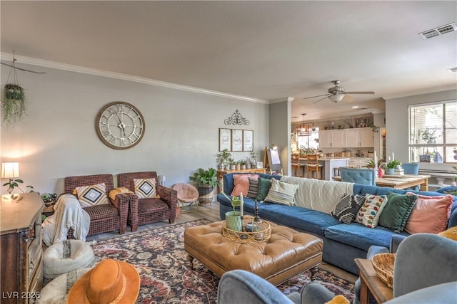 living room featuring visible vents, wood finished floors, ceiling fan, and crown molding