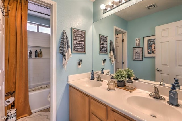 full bath featuring visible vents, toilet, double vanity, and a sink
