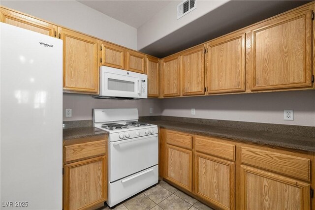 10001 Peace Way Unit 2228, Las Vegas, NV 89147 - kitchen with white appliances, light tile patterned floors, and dark countertops