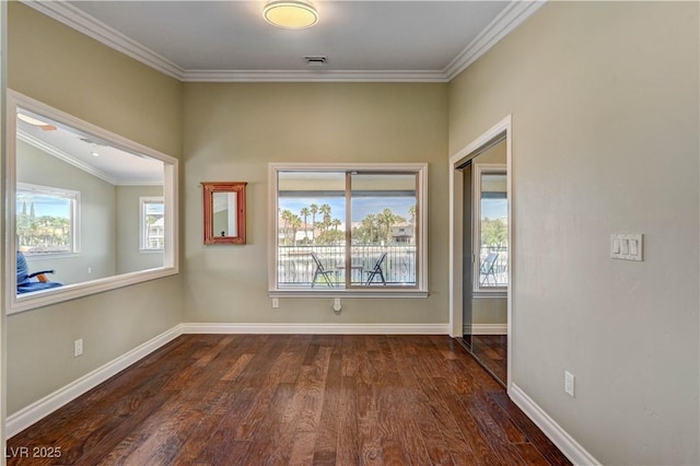 unfurnished room with crown molding, visible vents, dark wood-style flooring, and baseboards