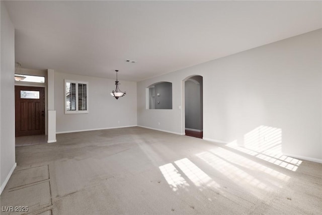 240 Jumping Springs Pl, Henderson, NV 89012 - unfurnished living room with carpet floors, baseboards, arched walkways, and a chandelier