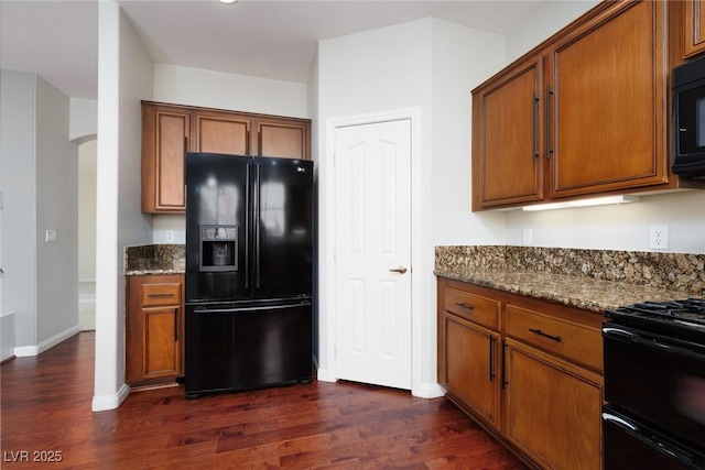 240 Jumping Springs Pl, Henderson, NV 89012 - kitchen featuring black appliances, dark wood-style flooring, brown cabinets, and dark stone countertops