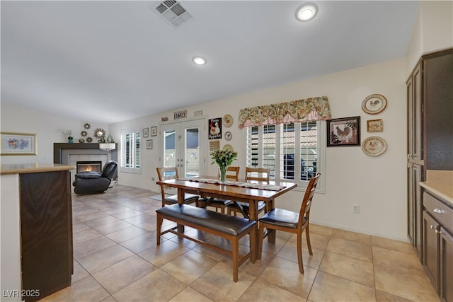 dining area with light tile patterned floors, a tile fireplace, visible vents, and a healthy amount of sunlight