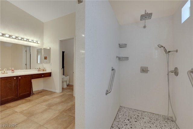 bathroom featuring tiled shower, toilet, and double vanity