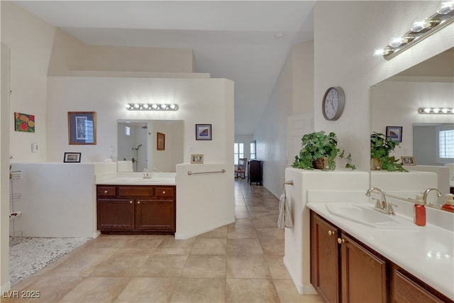 bathroom featuring two vanities, high vaulted ceiling, tile patterned flooring, and a sink