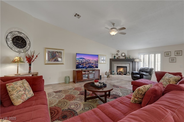 living room featuring a fireplace, a ceiling fan, visible vents, vaulted ceiling, and tile patterned flooring