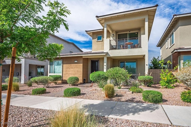 view of front of property with fence, a balcony, and stucco siding