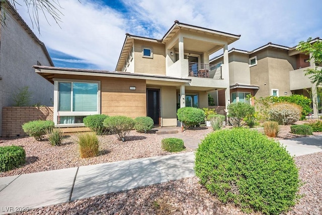 view of front of house featuring stucco siding and a balcony
