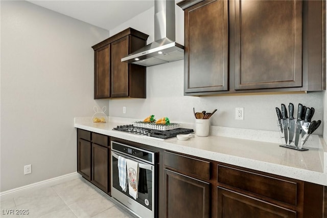 4630 Adonis Blue St, North Las Vegas, NV 89031 - kitchen with stainless steel appliances, wall chimney range hood, dark brown cabinetry, light stone countertops, and baseboards
