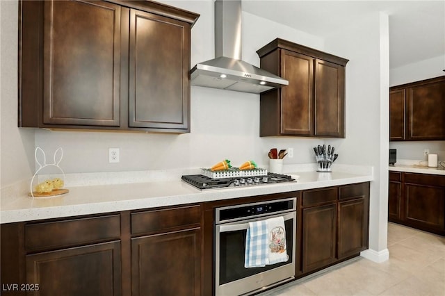 4630 Adonis Blue St, North Las Vegas, NV 89031 - kitchen featuring appliances with stainless steel finishes, wall chimney range hood, light countertops, dark brown cabinets, and light tile patterned flooring