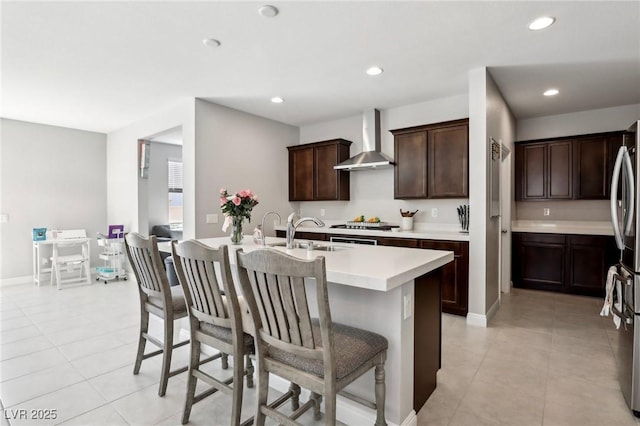 4630 Adonis Blue St, North Las Vegas, NV 89031 - kitchen with wall chimney range hood, a sink, a breakfast bar, light countertops, and dark brown cabinets
