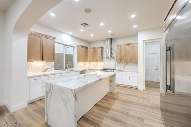 2571 Red Springs Dr, Las Vegas, NV 89135 - kitchen with light stone countertops, arched walkways, a kitchen island, visible vents, and wall chimney exhaust hood