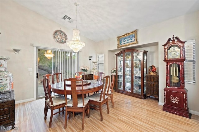 dining space featuring an inviting chandelier, light wood-type flooring, visible vents, baseboards, and lofted ceiling