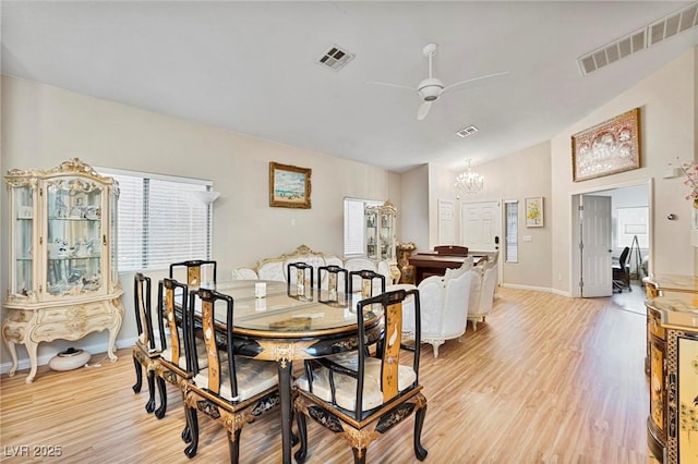 dining room featuring vaulted ceiling, light wood-style floors, visible vents, and ceiling fan with notable chandelier