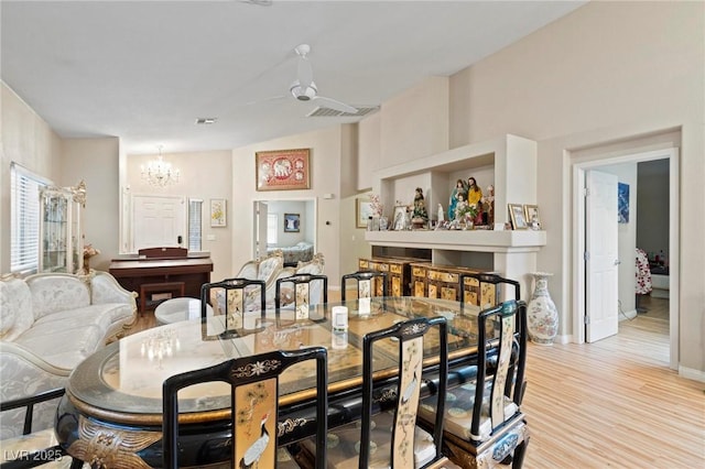 dining room with baseboards, light wood-type flooring, and ceiling fan with notable chandelier