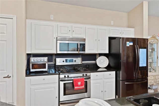 kitchen featuring stainless steel appliances, white cabinetry, and dark countertops