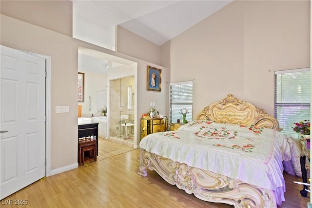 bedroom featuring light wood-style flooring, ensuite bathroom, high vaulted ceiling, and baseboards