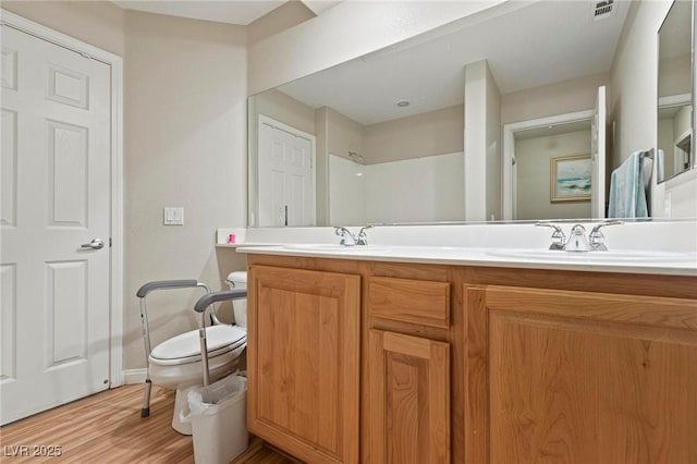 full bathroom featuring double vanity, toilet, wood finished floors, and a sink