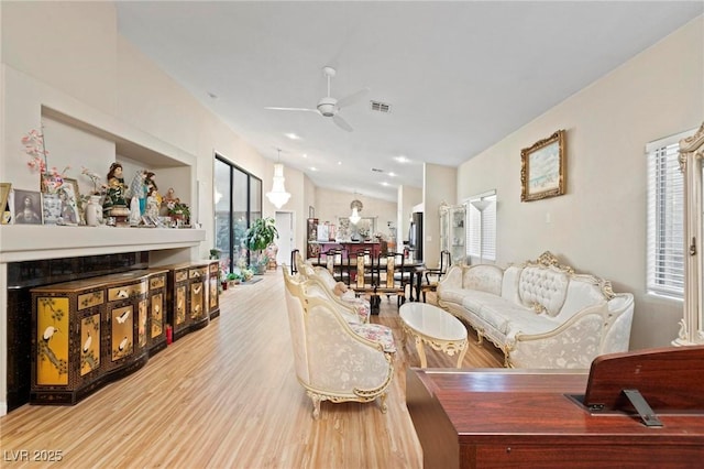 living area with lofted ceiling, visible vents, ceiling fan, and wood finished floors