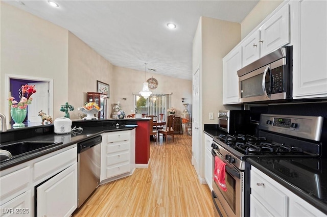 kitchen featuring a sink, dark countertops, light wood-type flooring, white cabinetry, and appliances with stainless steel finishes