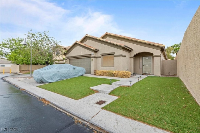 mediterranean / spanish home featuring a front yard, stucco siding, fence, and a garage