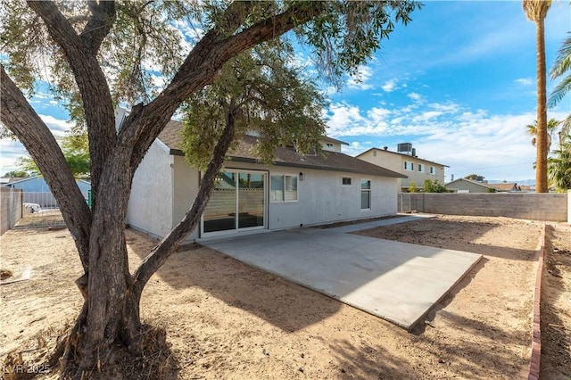 rear view of property featuring a patio, a shingled roof, a fenced backyard, and stucco siding