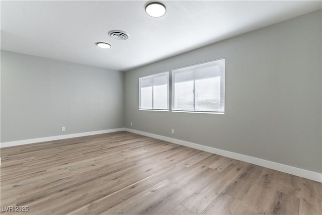 spare room featuring baseboards, visible vents, and light wood-style floors