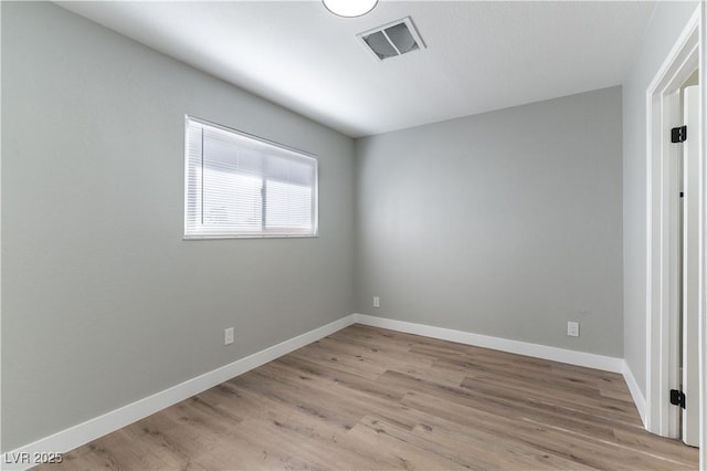 unfurnished room featuring light wood finished floors, visible vents, and baseboards